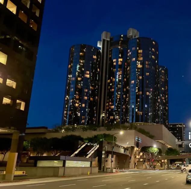 The Concrete Podium — the original hotel at blue hour. The cylindrical towers are striking, but the base is unambiguously hostile to pedestrians: a wall of concrete and ramps with no invitation to engage.